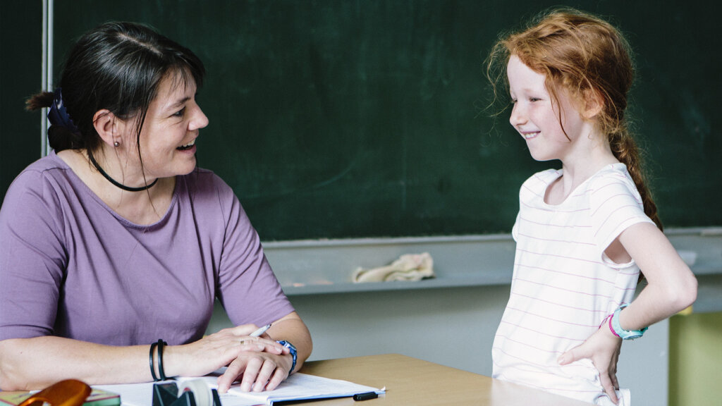 a teacher showing empathy while talking to a young student in the classroom