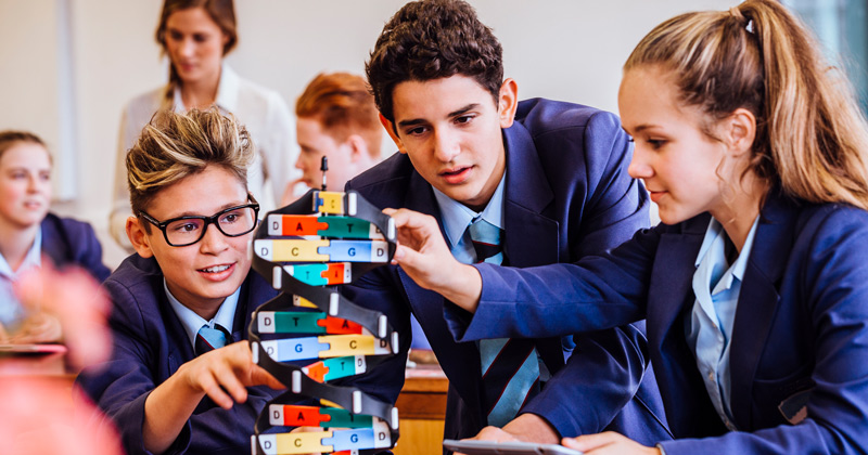 three students collaborating on an engineering project in the classroom